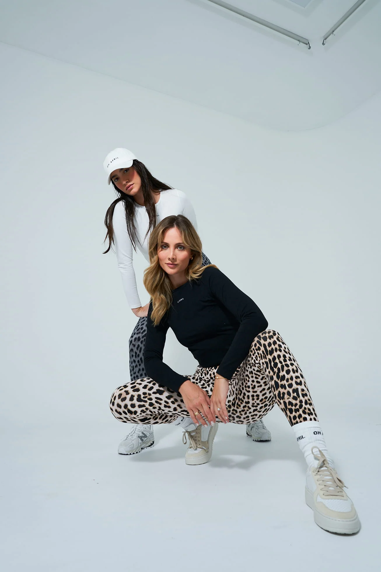 Two models in black tops and leopard print leggings