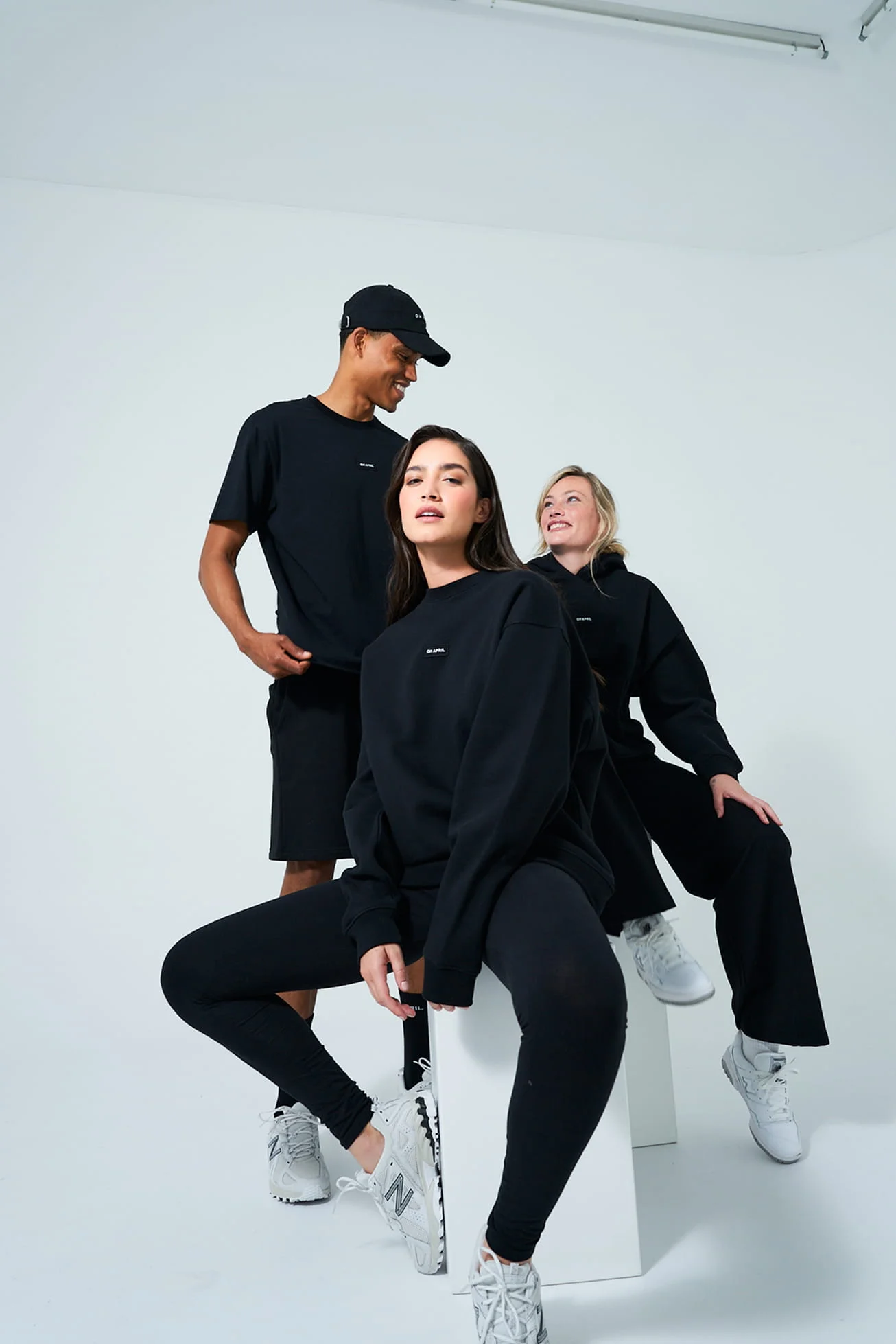 Three models in black outfits in a white studio