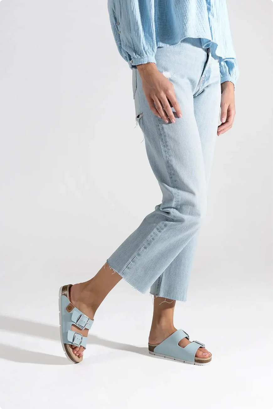 Model in light jeans wearing light blue two-strap sandals