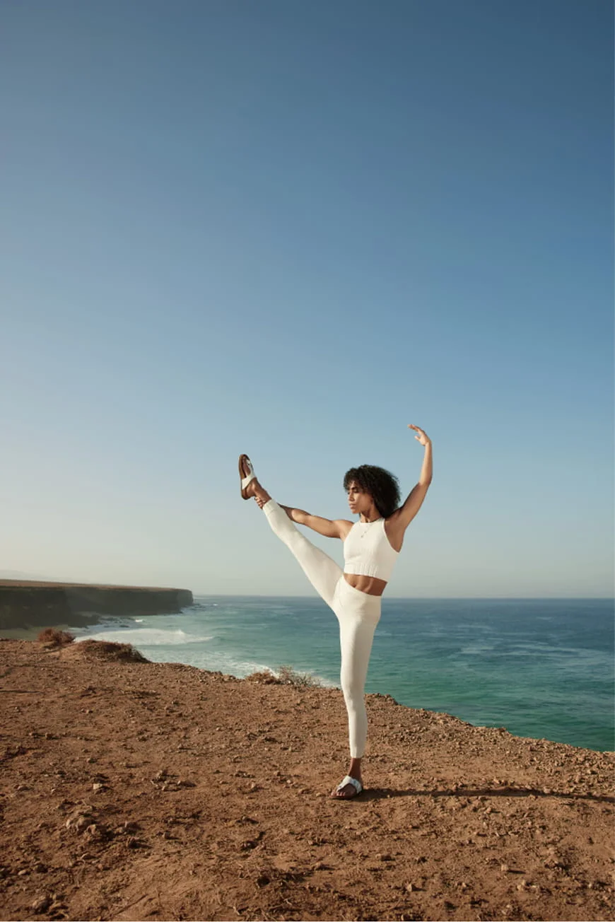 Woman doing a yoga pose by the sea.
