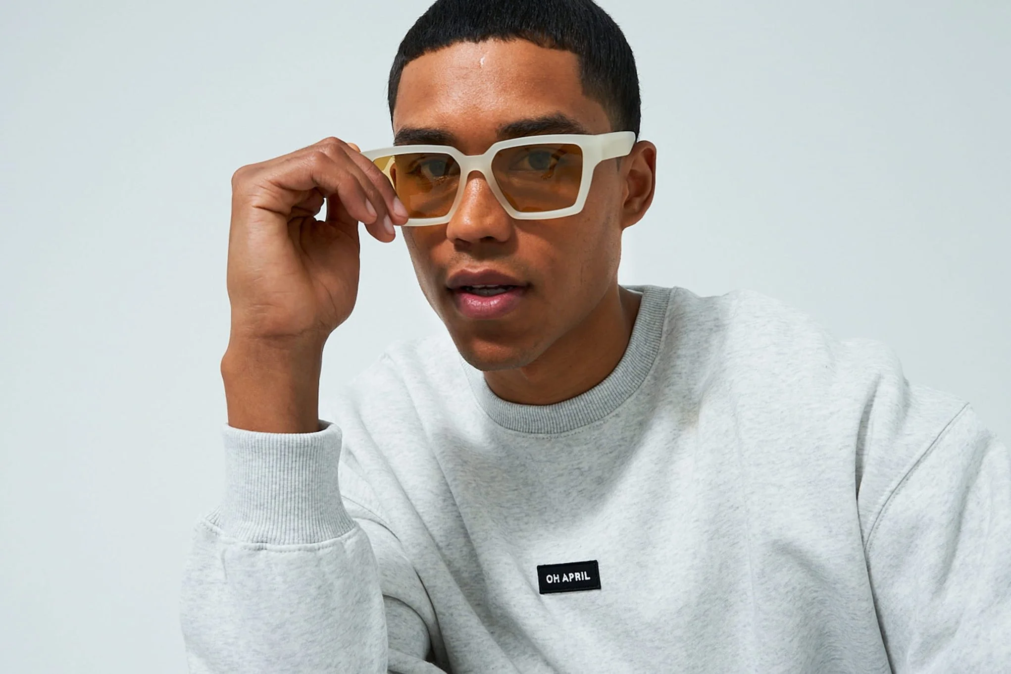 Model in a light grey sweatshirt with sunglasses