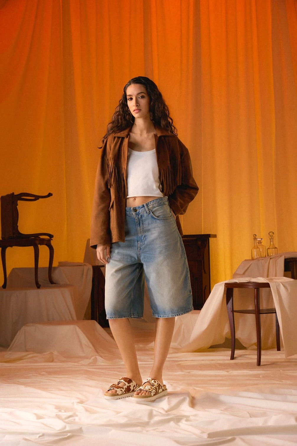 Frau in brauner Fransenjacke und Jeansshorts