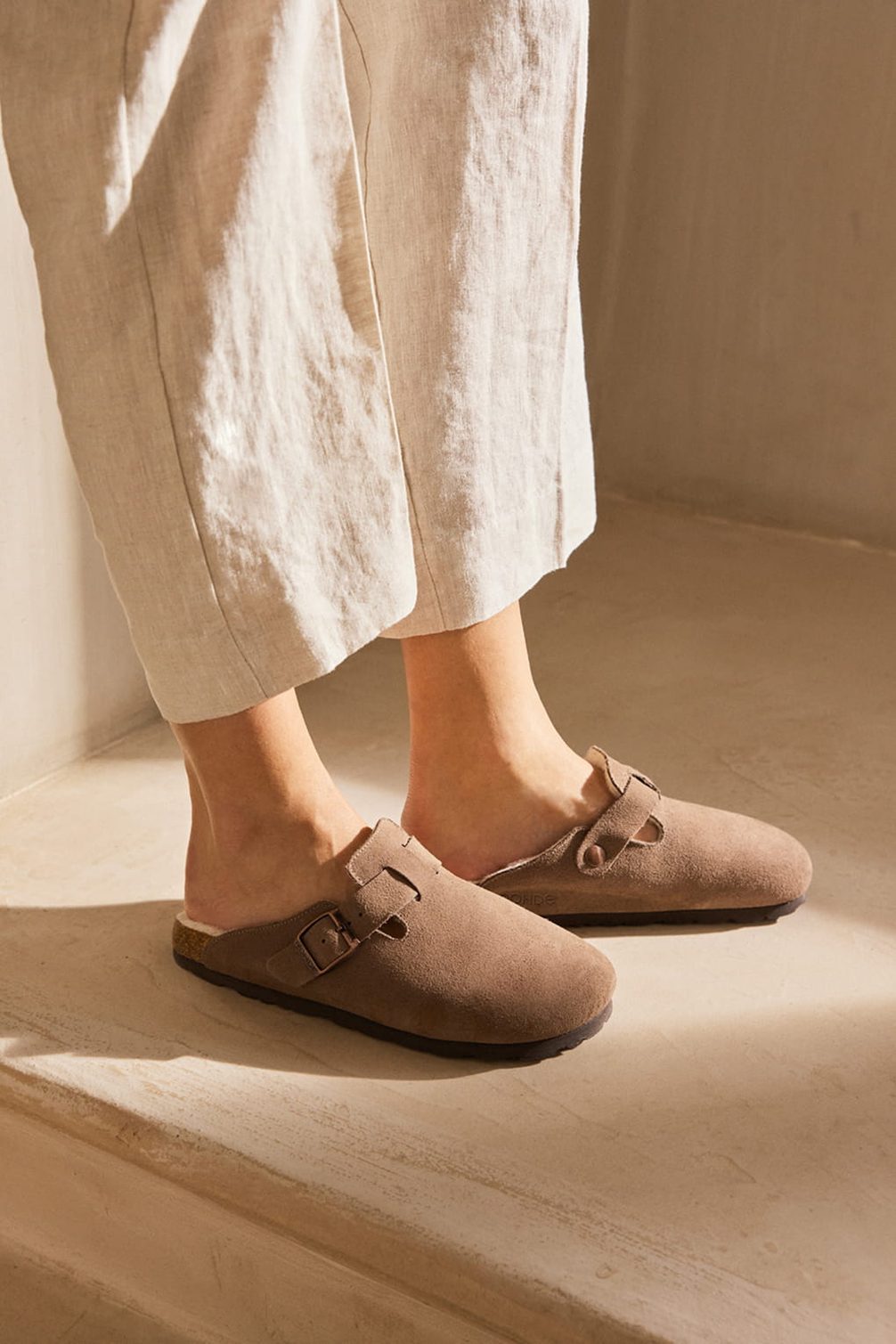 Braune Clogs aus Veloursleder mit Schnallen.