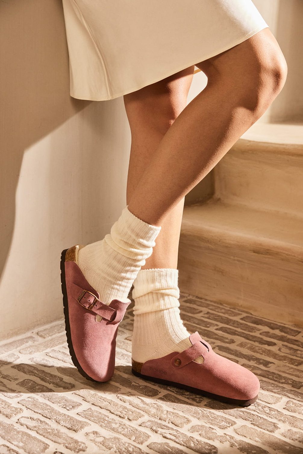 Rosa Clogs aus Veloursleder mit weißen Socken.