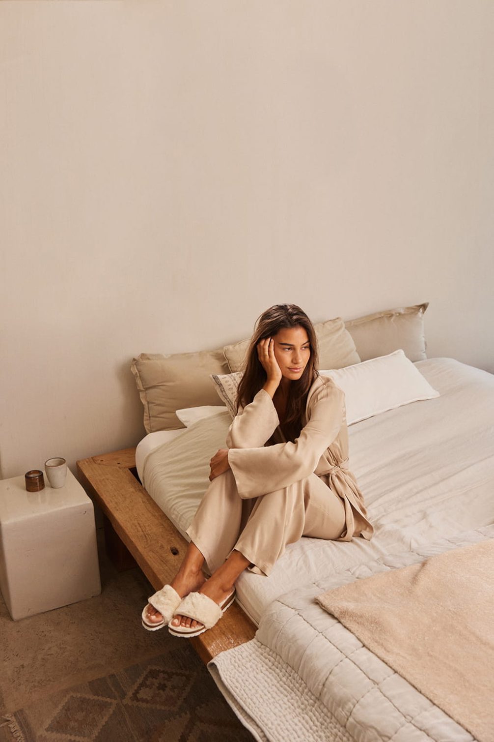 Frau in Loungewear entspannt auf einem Bett.