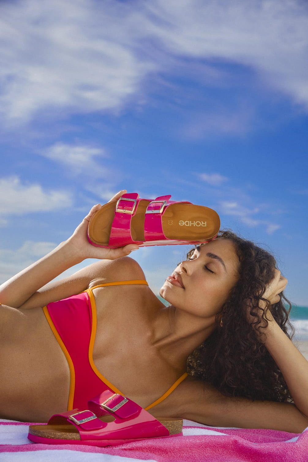Model mit rosa Sandalen am Strand